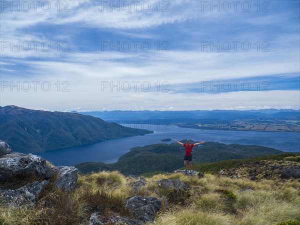 Portrait of hiker with arms outstretched in Fiordland National Park, Te Anau, Fiordland, New Zealand