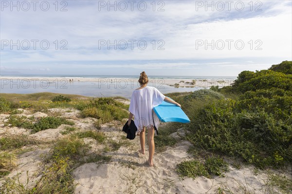 South Africa, Hermanus, Teenage girl walking on beach with body board, Hermanus, , South Africa