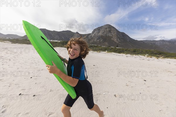 South Africa, Hermanus, Smiling boy running on beach with body board, Hermanus, , South Africa