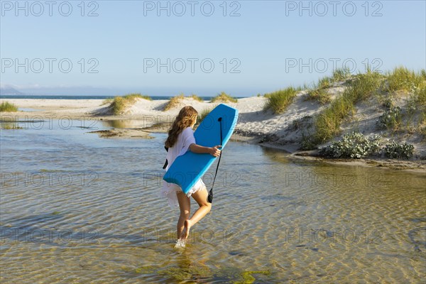 South Africa, Hermanus, Teenage girl walking on beach with body board, Hermanus, , South Africa