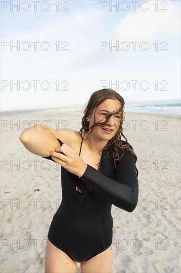 South Africa, Hermanus, Teenage girl putting on wetsuit on beach, Hermanus, , South Africa