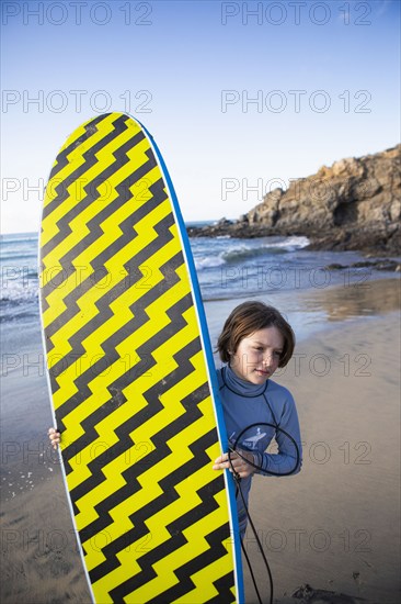 Mexico, Baja, Pescadero, Boy carrying surfboard on beach, Pescadero, Baja, Mexcio