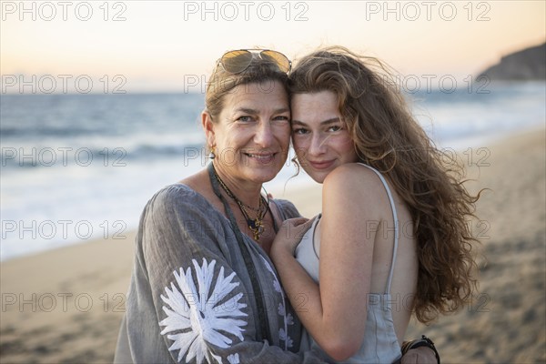 Portrait of smiling mother and teenage daughter on beach, Pescadero, Baja, Mexcio