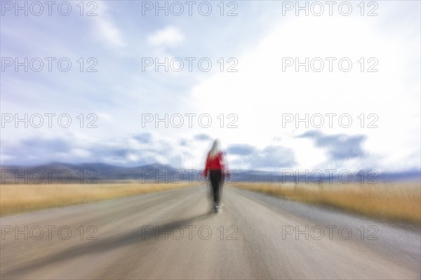 Rear view of woman walking on rural road, blurred motion, Bellevue, Idaho, USA