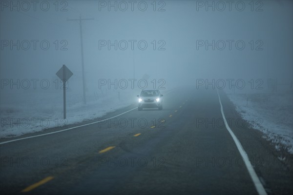 Car on Idaho 20 road in heavy fog at dusk, Mountain Home, Idaho, USA