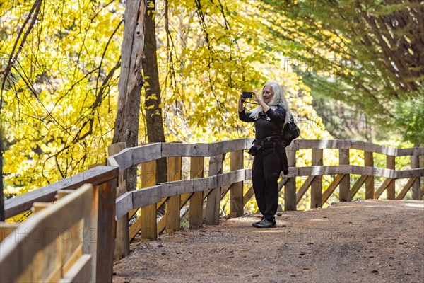 Smiling woman with long white hair photographing landscape with smart phone, Bariloche, Rio Negro, Argentina