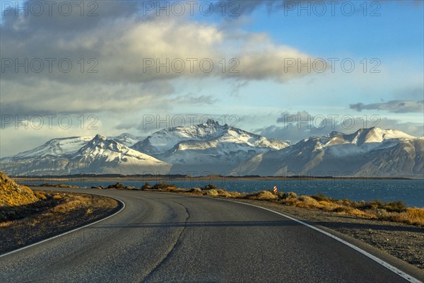 Argentina, Santa Cruz, El Calafate, Empty road with lake and snowcapped mountains in background, El Calafate, Santa Cruz, Argentina