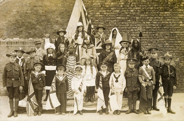 Children of the British Empire. A group of children holding union jack flags pose for a portrait, dressed in British Empire costumes. The boys wear a variety of military uniforms whilst the girls are dressed more theatrically as characters ranging from bedouins to African tribal women. Probably England, circa 1908. England (United Kingdom), Western Europe, Europe .