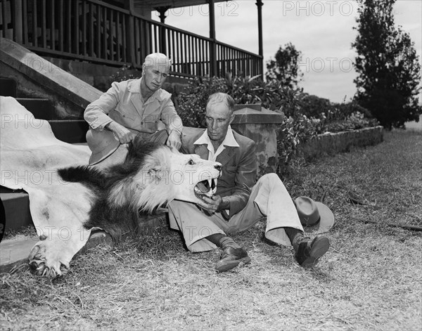 Clifford and Harold with lion skin. Clifford and Harold Hill seated with a lion skin on the steps of a veranda. Kenya, 9 September 1954. Kenya, Eastern Africa, Africa.