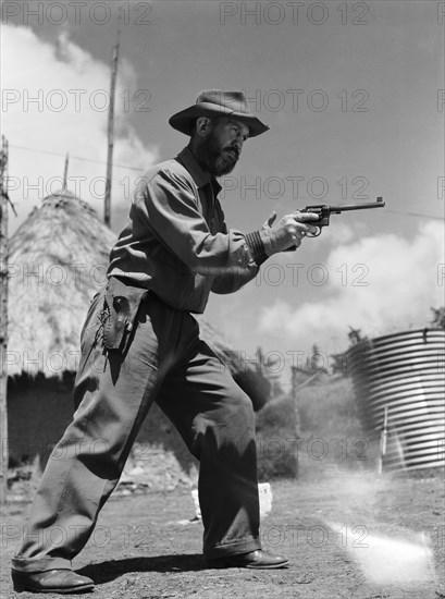 Davo' Davidson takes aim. Davo' Davidson aims a revolver. Kenya, 22 May 1953. Kenya, Eastern Africa, Africa.