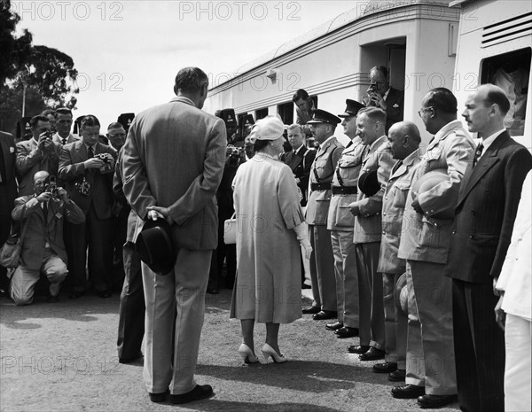 The Queen Mother visits Kenya. A publicity photograph from the East African Railways and Harbours Administration (EAR&H). Journalists take pictures of Queen Elizabeth, the Queen Mother, as she greets uniformed officials and railway staff at a stop made by the royal train on her tour of Kenya and Uganda. Kenya, February 1959. Kenya, Eastern Africa, Africa.