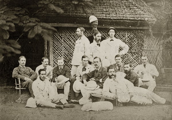 Satara and Poona cricket teams. Group portrait of the Satara and Poona cricket teams dressed in their whites. One of the players holds up a model head wearing a hat, presumbaly indicating the position of an absent team member. Bombay (Mumbai), India, circa 1875. Mumbai, Maharashtra, India, Southern Asia, Asia.