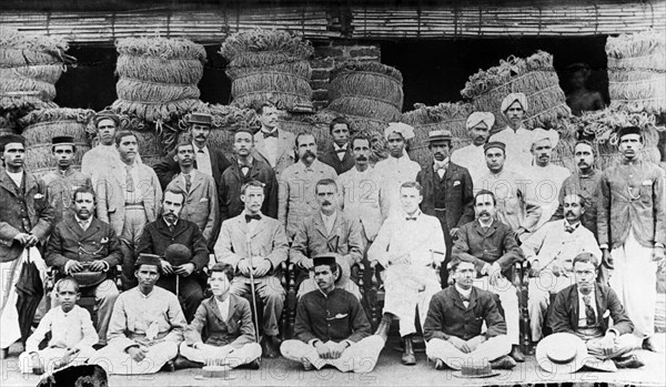 Steel Brothers employees. Portrait of a group of mainly Burmese employees working for Steel Brothers & Co. Ltd. The group is pictured against a backdrop of bundled twine. Probably Burma (Myanmar), circa 1910. Burma (Myanmar), South East Asia, Asia.