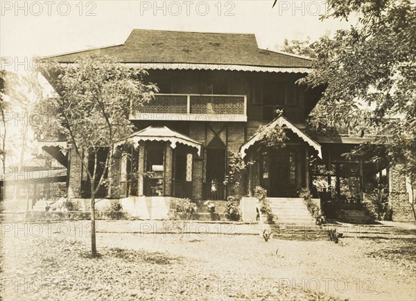 Colonial house in Burma (Myanmar). Exterior view of a colonial house, constructed from bricks with an ornate second-storey balcony and gabled porch. Burma (Myanmar), circa 1910. Burma (Myanmar), South East Asia, Asia.