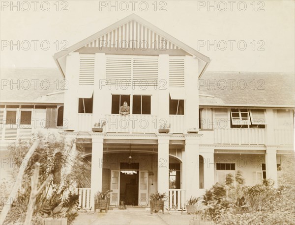 Walter Steel at his colonial-style house. Walter Steele, a British colonial administrator in Nigeria, leans out of a second-storey window from his colonial-style house. Lagos, Nigeria, 1920. Lagos, Lagos, Nigeria, Western Africa, Africa.