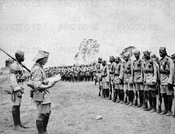 King's African Rifles depart for war. A European officer reads instructions to a line of African askaris (soldiers) in the First and Second Battalions of the King's African Rifles. British East Africa (Kenya), 4 August 1916. Kenya, Eastern Africa, Africa.