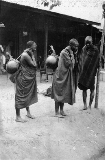 Milk sellers at Machakos. Two female milk sellers carry large gourds on their backs slung over their shoulders and supported by a thong over the forehead. Machakos, Kenya, 1927. Machakos, East (Kenya), Kenya, Eastern Africa, Africa.