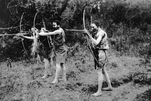 Nandi youths during circumcision rites. Three Nandi youths in seclusion during their circumcision rites take aim with bows and arrows. The boys' faces are painted. Kapsabet, Kenya, February 1928. Kapsabet, Rift Valley, Kenya, Eastern Africa, Africa.