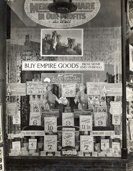 Empire goods from home and overseas. Signs in a shop window advertise a variety of Australian food products and prices. A central sign reads 'BUY EMPIRE GOODS FROM HOME AND OVERSEAS'. Location unknown, circa 1910.