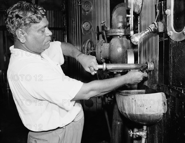 Testing samples at a sugar mill. An Indian worker tests a sample of sugar from an industrial machine covered in dials and gauges at the Miwani Sugar Mills. Miwani, Kenya, 7-8 November 1955. Miwani, Nyanza, Kenya, Eastern Africa, Africa.