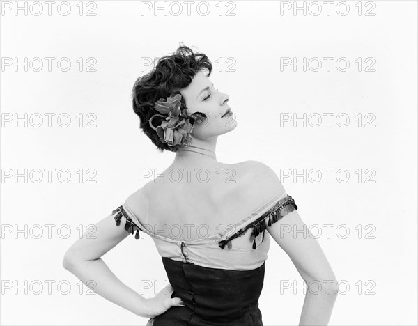 Profile shot of Daphne Dale. Profile portrait of dancer Daphne Dale in the role of Carmen. Dressed in theatrical costume, she wears a low cut bodice with bare arms and a decorative flower in her hair. Kenya, 15 November 1955. Uganda, Eastern Africa, Africa.