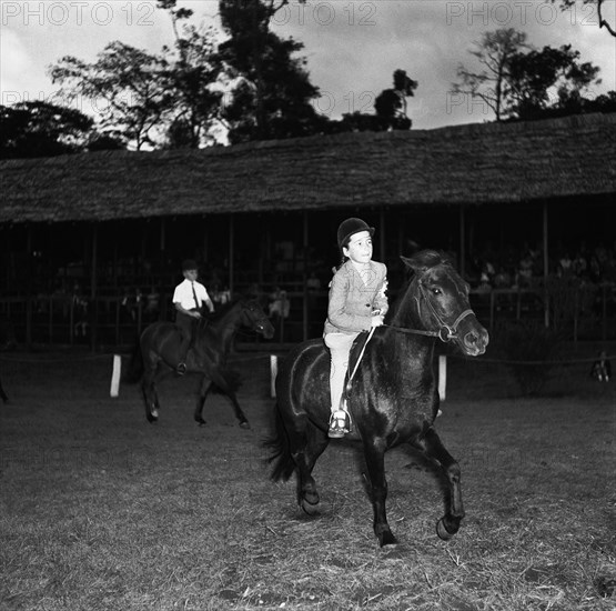 Pony competition at the SJAK show. A young girl rides a pony in the class two child's pony competition at the SJAK show (Sports Journalists Association of Kenya). Kenya, 20 August 1955. Kenya, Eastern Africa, Africa.