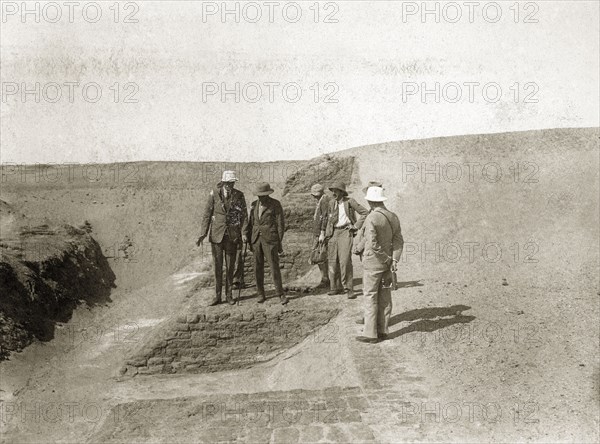 Archaeological excavation. European men with cameras or recording equipment walk along an exposed wall on a visit by the Governor General to the archaeological excavation of a twelfth dynasty fort. North East Africa, 1932., Northern Africa, Africa.