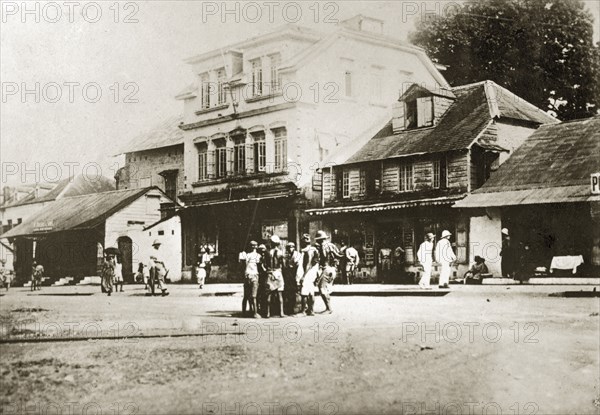 A main street in Sierra Leone. Africans and Europeans mill about on a wide main road in the centre of a large town, flanked by buildings of different styles. Sierra Leone, 8-13 December 1923., West (Sierra Leone), Sierra Leone, Western Africa, Africa.