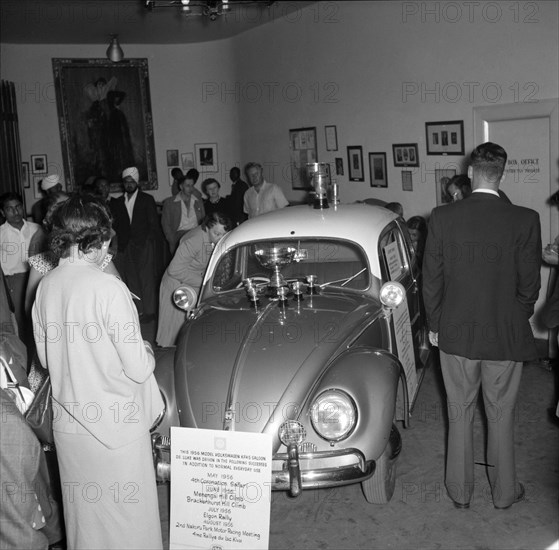 Volkswagen exhibition at the national theatre. An award-winning Volkswagen car on show inside the national theatre building is surrounded by guests. Signs around the car list races it has won and trophies on its bonnet show off its successes. Nairobi, Kenya, 22 August 1956. Nairobi, Nairobi Area, Kenya, Eastern Africa, Africa.