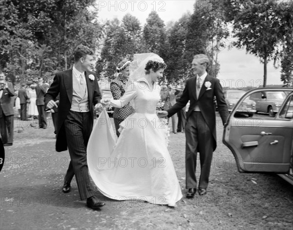 Newlywed runaways. The best man opens the door for the newlywed Patterson couple as they dash towards their wedding car. Kenya, 29 September 1956. Kenya, Eastern Africa, Africa.