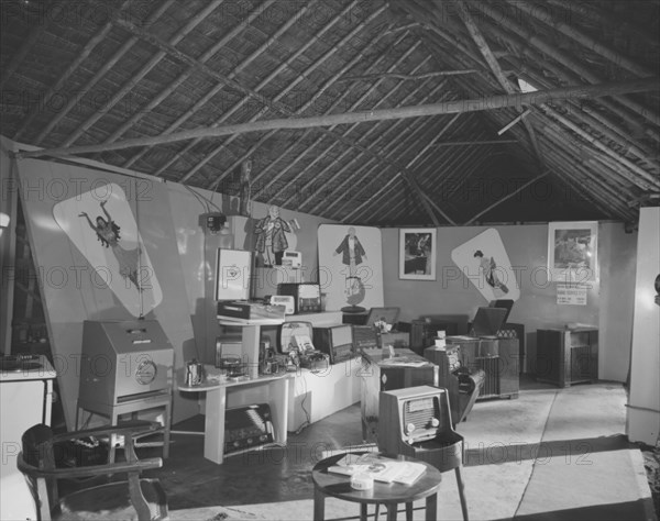 Luxor Radio at the Royal Show. Posters and advertising decorate the walls of the Luxor Radio stand at the Royal Show. Luxor radios in all shapes and sizes are on display in the exhibition space. Kenya, 17-20 October 1956. Kenya, Eastern Africa, Africa.