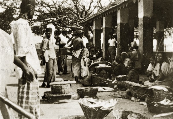 Ceylonian street market. Street traders sell goods from baskets on the floor at a busy open air market. Trincomali, Ceylon (Sri Lanka), 27-31 January 1924. Trincomali, East (Sri Lanka), Sri Lanka, Southern Asia, Asia.