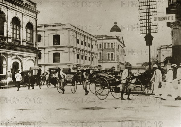 Rickshaw pullers in Penang. Barefoot rickshaw pullers compete for business at a busy crossroad in the centre of town. Penang, British Malaya (Malaysia), 4-8 February 1924., Penang, Malaysia, South East Asia, Asia.