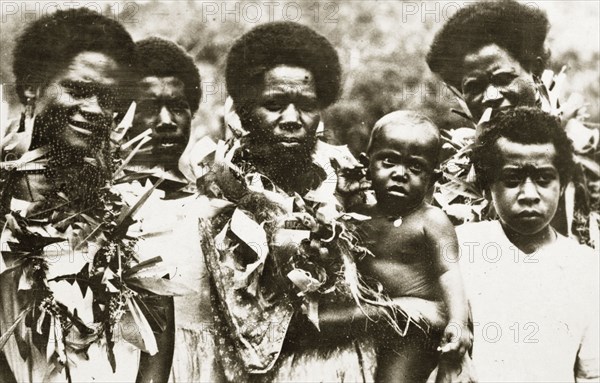 Fijian people. Portrait of a group of Fijian people with a baby. The three women pictured wear garlands of leaves around their necks. Fiji, 21-27 May 1924. Fiji, Pacific Ocean, Oceania.