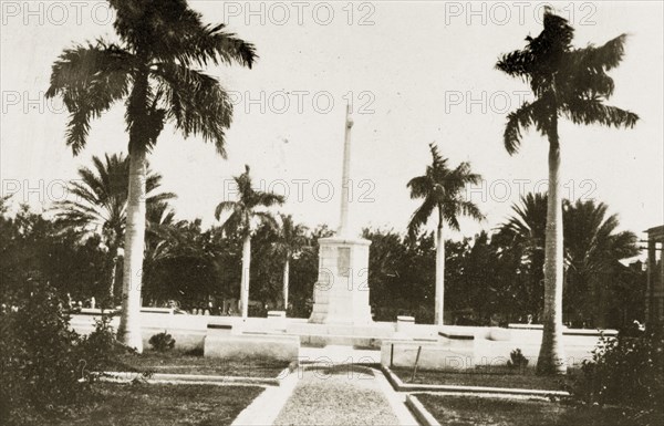 War memorial, Kingston. A war memorial stands in front of government buildings bordered by palm trees. Kingston, Jamaica, 26-30 July 1924. Kingston, Kingston, Jamaica, Caribbean, North America .