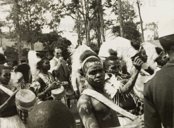 Drummers in traditional dress at the Royal Show. A group of Kenyan men wear traditional fur headdresses and beaded chest jewellery as they parade, playing drums at the Nairobi Royal Show. Nairobi, Kenya, circa 1956. Nairobi, Nairobi Area, Kenya, Eastern Africa, Africa.