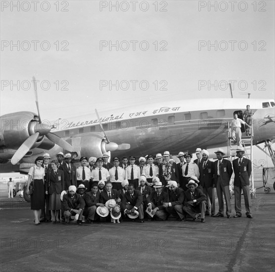 Olympic teams arrive in Bombay. Olympic teams arrive in Bombay, posing for the camera with flight staff on the runway in front of their plane. The Kenyan team's mascot, a lion, can be seen in the front row. Bombay (Mumbai), India, 2 November 1956. Mumbai, Maharashtra, India, Southern Asia, Asia.