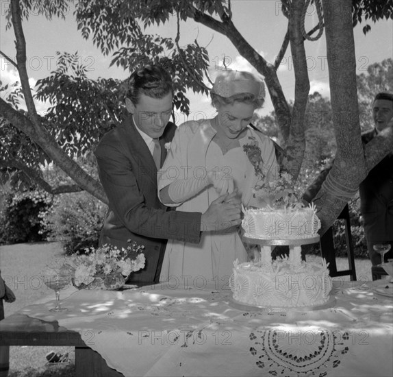 The Rowe and Jones couple cut the cake. The newlywed Rowe and Jones couple cut the cake on their wedding day. Kenya, 8 December 1956. Kenya, Eastern Africa, Africa.