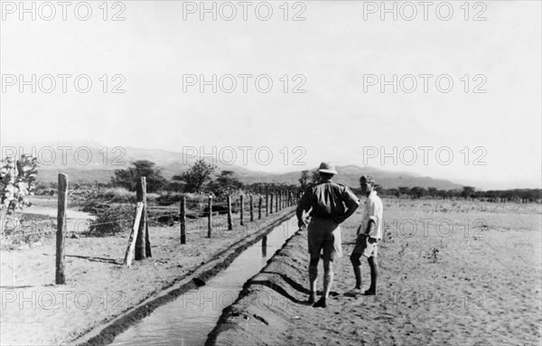 Rehabilitation scheme for Mau Mau detainees. Two Europeans inspect an irrigation channel, constructed by Mau Mau detainees as part of a rehabilitation scheme. Near Embu, Kenya, circa 1954. Embu, East (Kenya), Kenya, Eastern Africa, Africa.