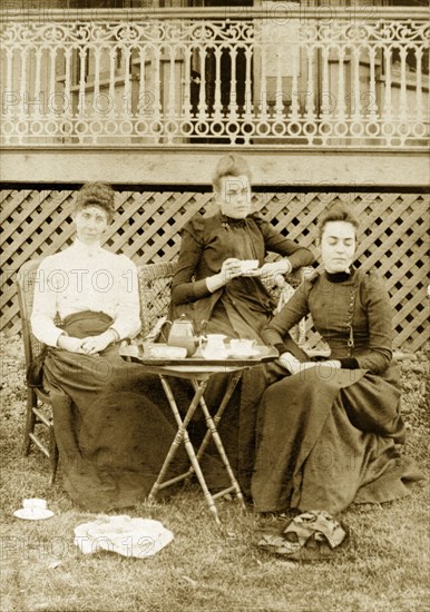 Katie, Prue and Ellie take tea, Australia. Members of the Brodribb family relax, looking thoughtful, around an outdoor table, a tea set laid out before them. Toowoomba, Australia, circa 1908. Toowoomba, Queensland, Australia, Australia, Oceania.