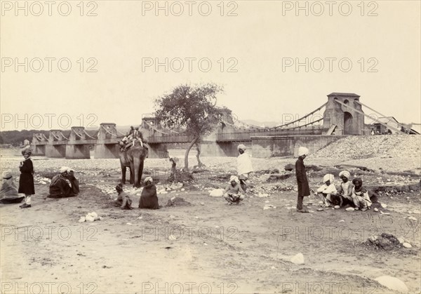 The entrance to Kashmir. A group of men with an elephant wait near a river bridge at the entrance to the disputed territory of Kashmir. Jammu, India, circa 1895. Jammu, Jammu and Kashmir, India, Southern Asia, Asia.