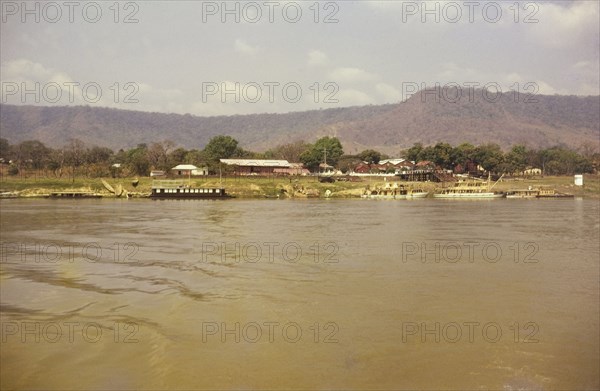 Lokoja trading houses. View across the river of ferries docked beside the Royal Niger Company trading houses. Lokoja, Nigeria, circa 1965. Lokoja, Kogi, Nigeria, Western Africa, Africa.