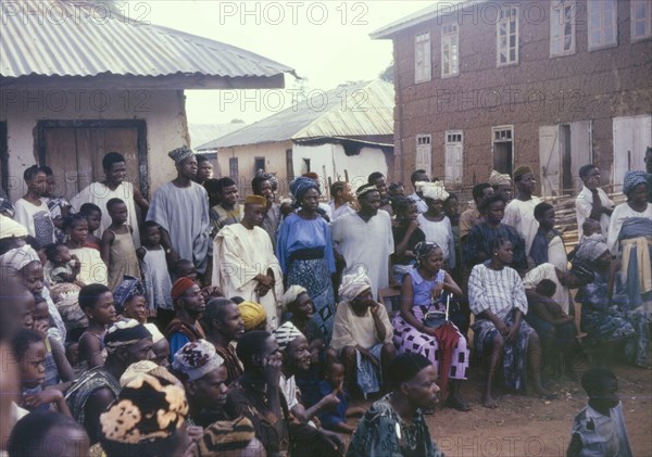 An audience of onlookers. A crowd of spectators are captivated by a performance happening just out of shot. An original caption suggests this may be an Easter celebration connected with the Church of Nigeria. Nigeria, circa 1963. Nigeria, Western Africa, Africa.