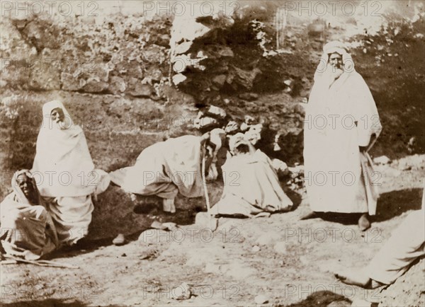 Group of Morrocan men. A group of Moroccan men dressed in white robes rest at a ruin in the desert. A caption suggests that Frederick Stanbury visited these people on an excursion during his travels in Morocco. Morocco, 1898. Morocco, Northern Africa, Africa.