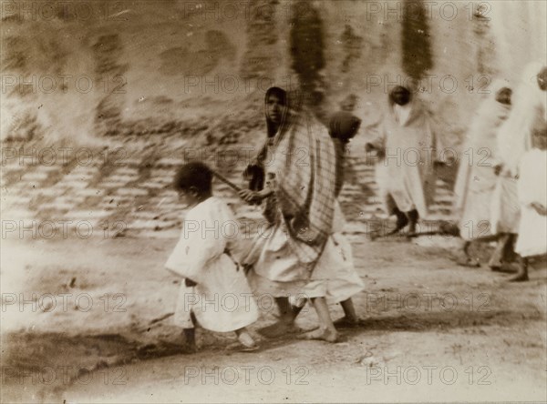 Morrocan woman and children. A young Moroccan woman, her head covered with a scarf, marshals her children through the city streets, Morocco, 1898. Morocco, Northern Africa, Africa.