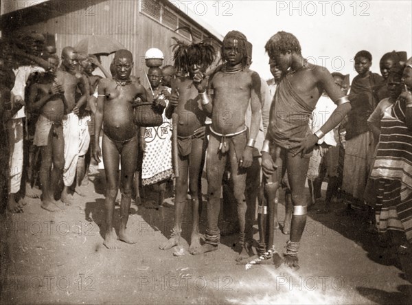 Luo youths at Kisumu market. A group of African youths, probably Luo, gather outside a local market. Kisumu, British East Africa (Kenya), 1906. Kisumu, Nyanza, Kenya, Eastern Africa, Africa.