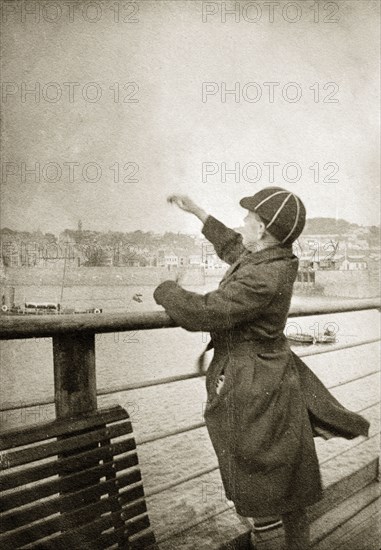 Charles Trotter on a pier. Charles Trotter, aged about 12 years old, throws pebbles into the sea from an English pier. South coast, England, circa 1935. England (United Kingdom), Western Europe, Europe .