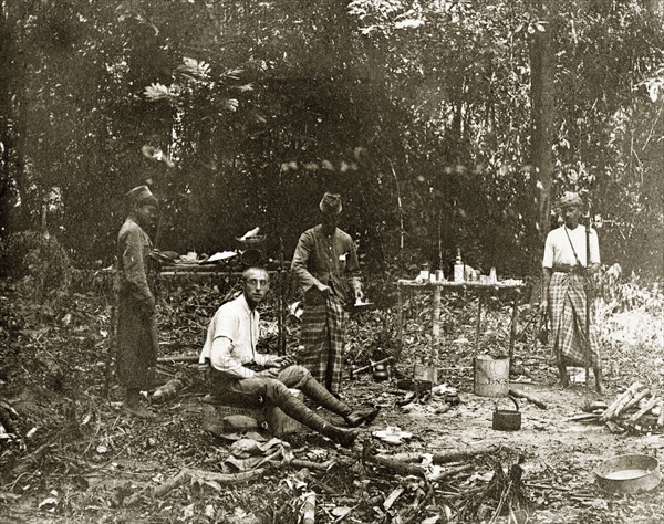 Sheffield's' jungle camp, Malaysia. Sheffield', a member of a British-led trigonometrical survey team, and his Malayan assistants stop for a meal in the jungle. Upper Perak, British Malaya (Malaysia), circa 1902., Perak, Malaysia, South East Asia, Asia.