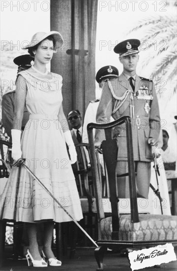 Queen Elizabeth II ready to perform an accolade, 1954. Queen Elizabeth II stands on an outdoor platform holding a ceremonial sword in preparation to perform an accolade on a subject, during her visit to Aden as part of a royal tour of the Commonwealth from November 1953 to May 1954. Aden, Yemen, 27 April 1954. Aden, Adan, Yemen, Middle East, Asia.