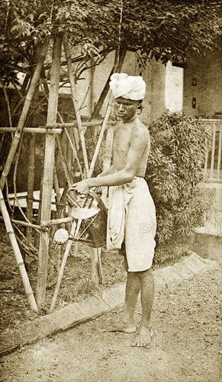 Watering the garden, India. A turbaned Indian man sprinkles water onto a dusty garden from a watering can. India, circa 1890. India, Southern Asia, Asia.